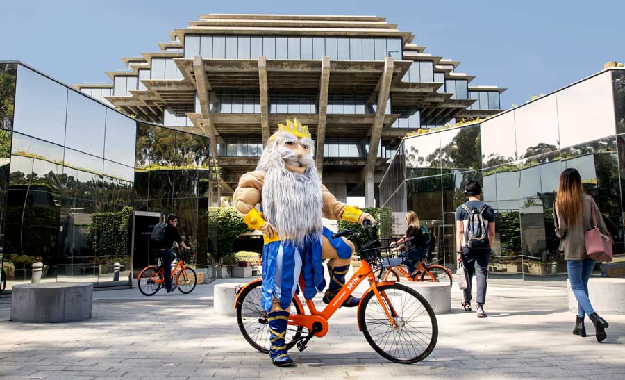 UC San Diego's King Triton Mascot on a SPIN bicycle in front of Geisel Library